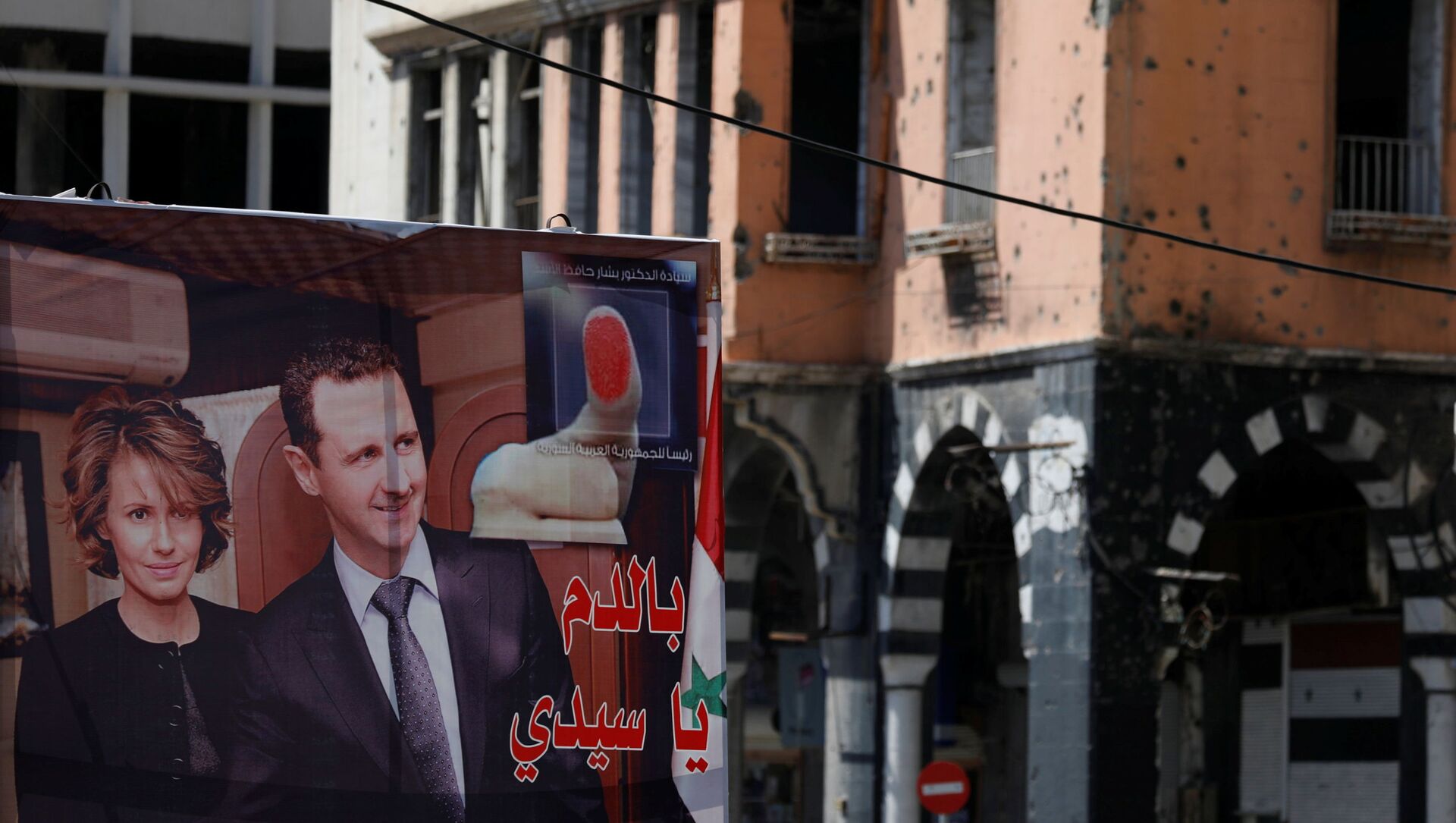 A view shows a banner depicting Syria's President Bashar al-Assad and his wife Asma, near a damaged building, ahead of the May 26 presidential election, in Homs, Syria May 23, 2021. - Sputnik International, 1920, 28.05.2021