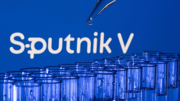 est tubes are seen in front of a displayed Sputnik V logo in this illustration taken, May 21, 2021. - Sputnik International