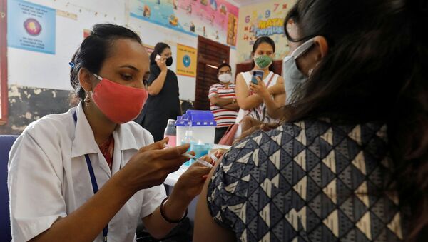 A healthcare worker gives a dose of COVISHIELD, a coronavirus disease (COVID-19) vaccine manufactured by Serum Institute of India, to a woman inside a classroom of a school, which has been converted into a temporary vaccination centre, in Ahmedabad, India, May 1, 2021 - Sputnik International