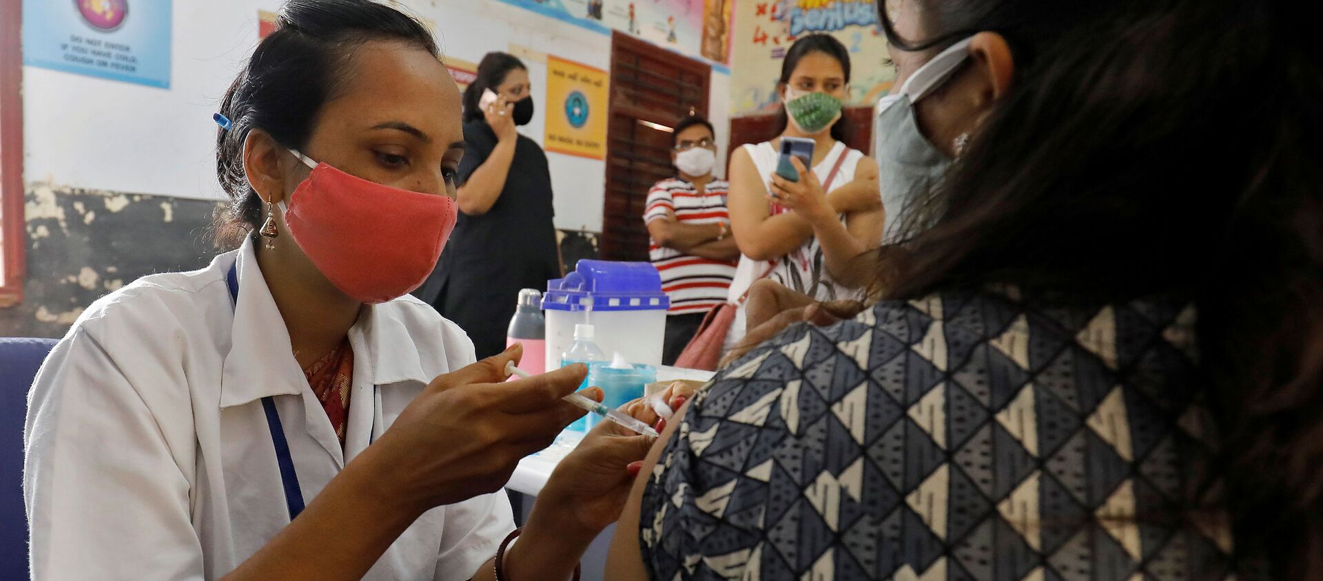 A healthcare worker gives a dose of COVISHIELD, a coronavirus disease (COVID-19) vaccine manufactured by Serum Institute of India, to a woman inside a classroom of a school, which has been converted into a temporary vaccination centre, in Ahmedabad, India, May 1, 2021 - Sputnik International, 1920