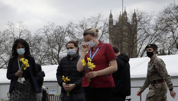 Members of NHS staff lay flowers after a minute of silence and reflection at St Thomas' hospital in London, Tuesday, March 23, 2021 - Sputnik International