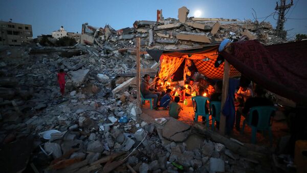 Palestinians from Zawaraa family hold candles as they sit in a makeshift tent amid the rubble of their houses which were destroyed by Israeli air strikes during the Israeli-Palestinian fighting in Gaza May 25, 2021. - Sputnik International