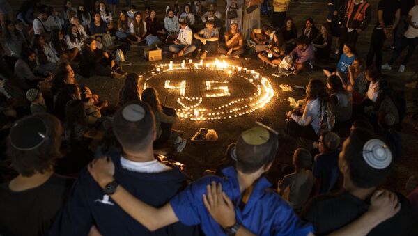 People gather around candles during a vigil in memory of the 45 ultra-Orthodox Jews killed in a stampede at a religious festival in northern Israel on Friday, in Tel Aviv, Israel, Sunday, 2 May 2021.  - Sputnik International