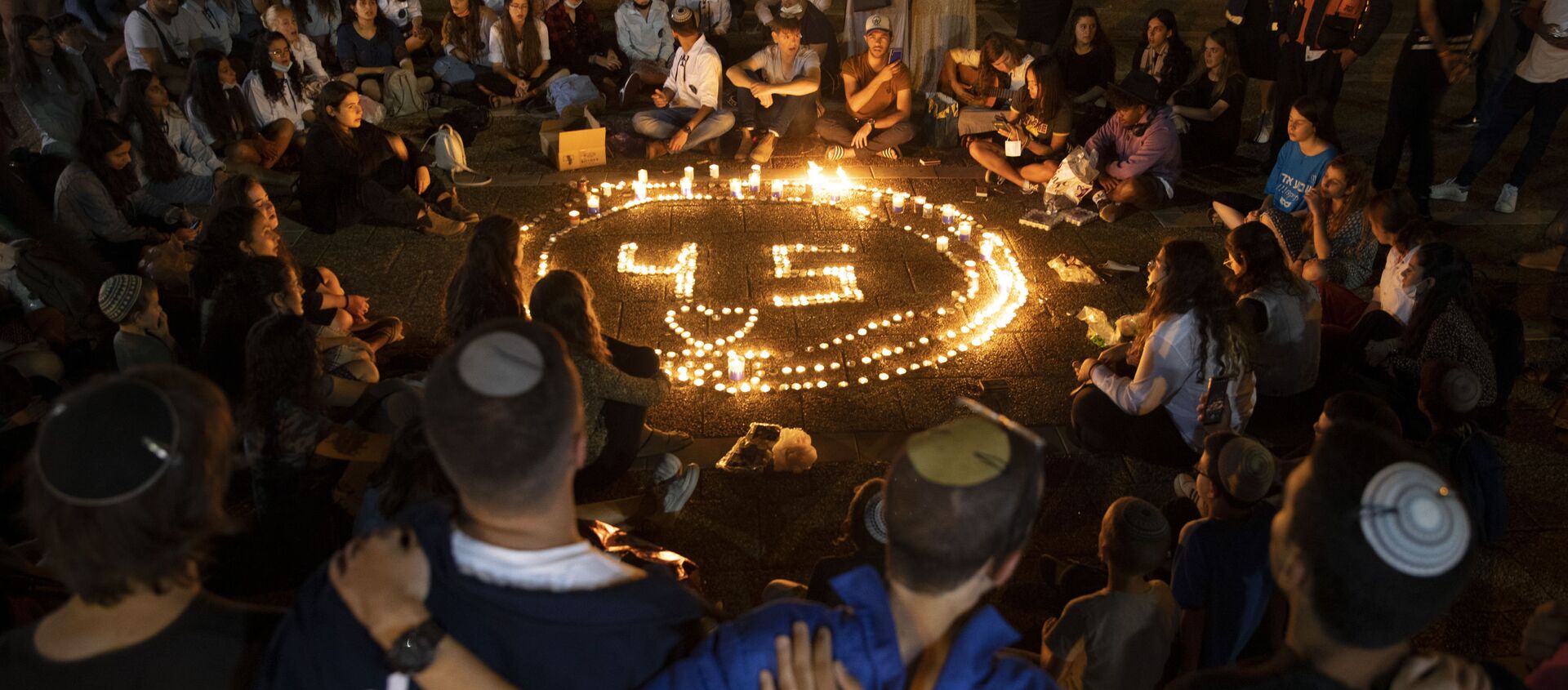 People gather around candles during a vigil in memory of the 45 ultra-Orthodox Jews killed in a stampede at a religious festival in northern Israel on Friday, in Tel Aviv, Israel, Sunday, 2 May 2021.  - Sputnik International, 1920, 30.05.2021