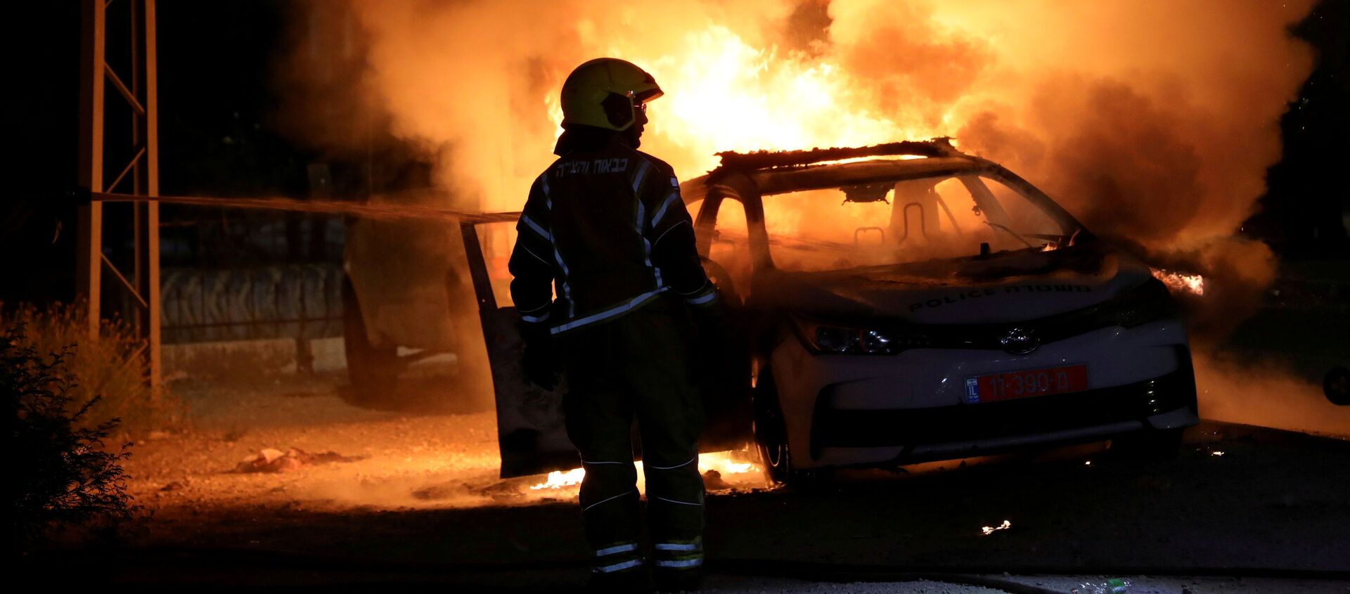 An Israeli firefighter stands near a burning Israeli police car during clashes between Israeli police and members of the country's Arab minority in the Arab-Jewish town of Lod, Israel May 12, 2021 - Sputnik International, 1920, 30.05.2021