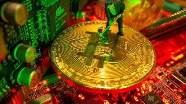 A small toy figure and representations of the virtual currency Bitcoin stand on a motherboard in this picture illustration taken May 20, 2021. - Sputnik International