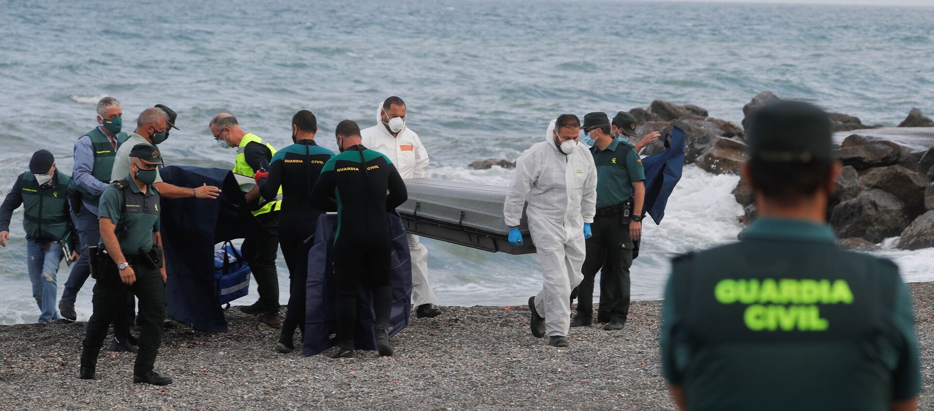 Workers carry a coffin containing a body at the shore near the Spanish-Moroccan border at El Tarajal Beach, after thousands of migrants swam across this border during the last days, in Ceuta, Spain, May 20, 2021 - Sputnik International, 1920, 31.05.2021