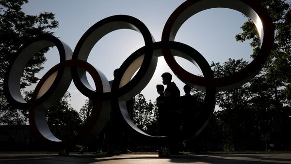 Visitors and the Olympic Rings monument are silhouetted outside the Japan Olympic Committee (JOC) headquarters near the National Stadium - Sputnik International