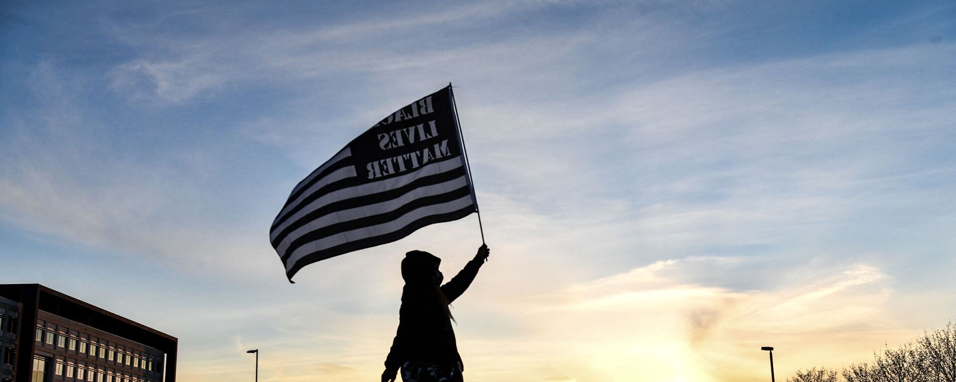 A demonstrator marches, holding a Black Lives Matter flag, during the sixth night of protests over the shooting death of Daunte Wright by a police officer in Brooklyn Center, Minnesota on April 16, 2021 - Sputnik International, 1920, 23.11.2021