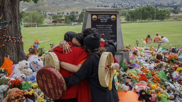 People from Mosakahiken Cree Nation hug in front of a makeshift memorial at the former Kamloops Indian Residential School to honour the 215 children whose remains have been discovered buried near the facility,  - Sputnik International