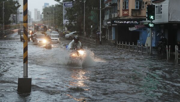 Commuters wade through a waterlogged street during a heavy rain in Mumbai, India, Monday, May 17, 2021 - Sputnik International