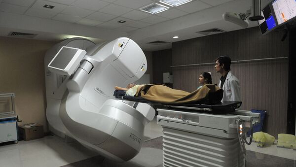Radiation technologist, Yogesh Ninave (R),  and coordinator, Khyati Panchal (L), observe a cancer patient lying in India's first Truebeam Radiotherapy Technology Linear Accelerator at the Healthcare Global hospital in Ahmedabad, in Gujarat state, on 13 December 2011. - Sputnik International