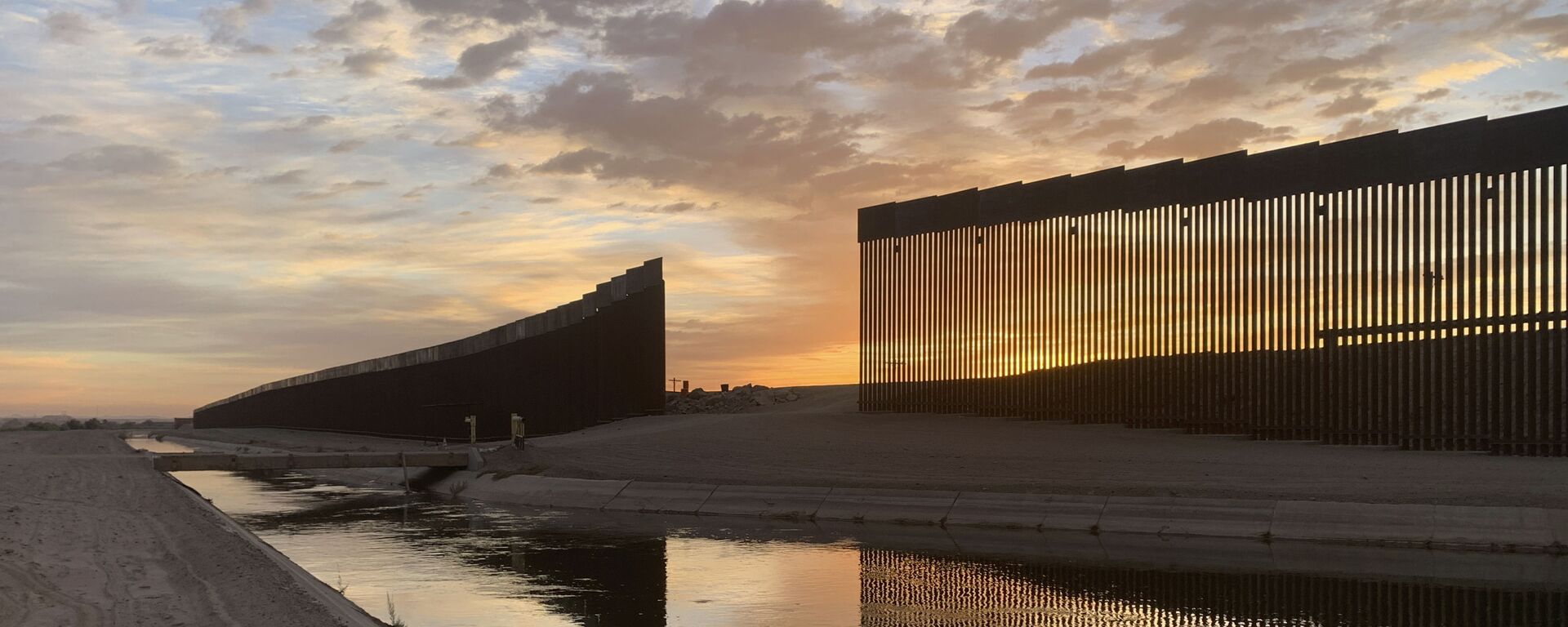 The sun sets above the U.S.-Mexico border wall, seen in Yuma, Ariz., Wednesday, June 9, 2021. The Biden administration says it has identified more than 3,900 children separated from their parents at the U.S.-Mexico border under former President Donald Trump's zero-tolerance policy on illegal crossings. - Sputnik International, 1920, 02.07.2022