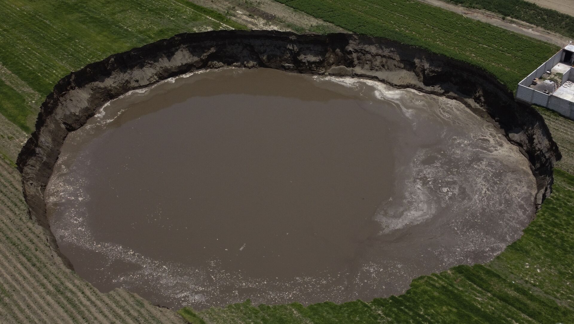 A water filled sinkhole grows in Zacatapec, on the outskirts of Puebla, Mexico, Tuesday, June 1, 2021. The massive water-filled sinkhole continues swallowing farmers' fields in the central Mexican state of Puebla. - Sputnik International, 1920, 15.06.2021