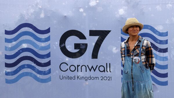 A pedestrian poses for a photograph with a G7 logo outside the media centre at Falmouth, Cornwall on June 10, 2021, ahead of the three-day G7 summit being held from 11-13 June - Sputnik International