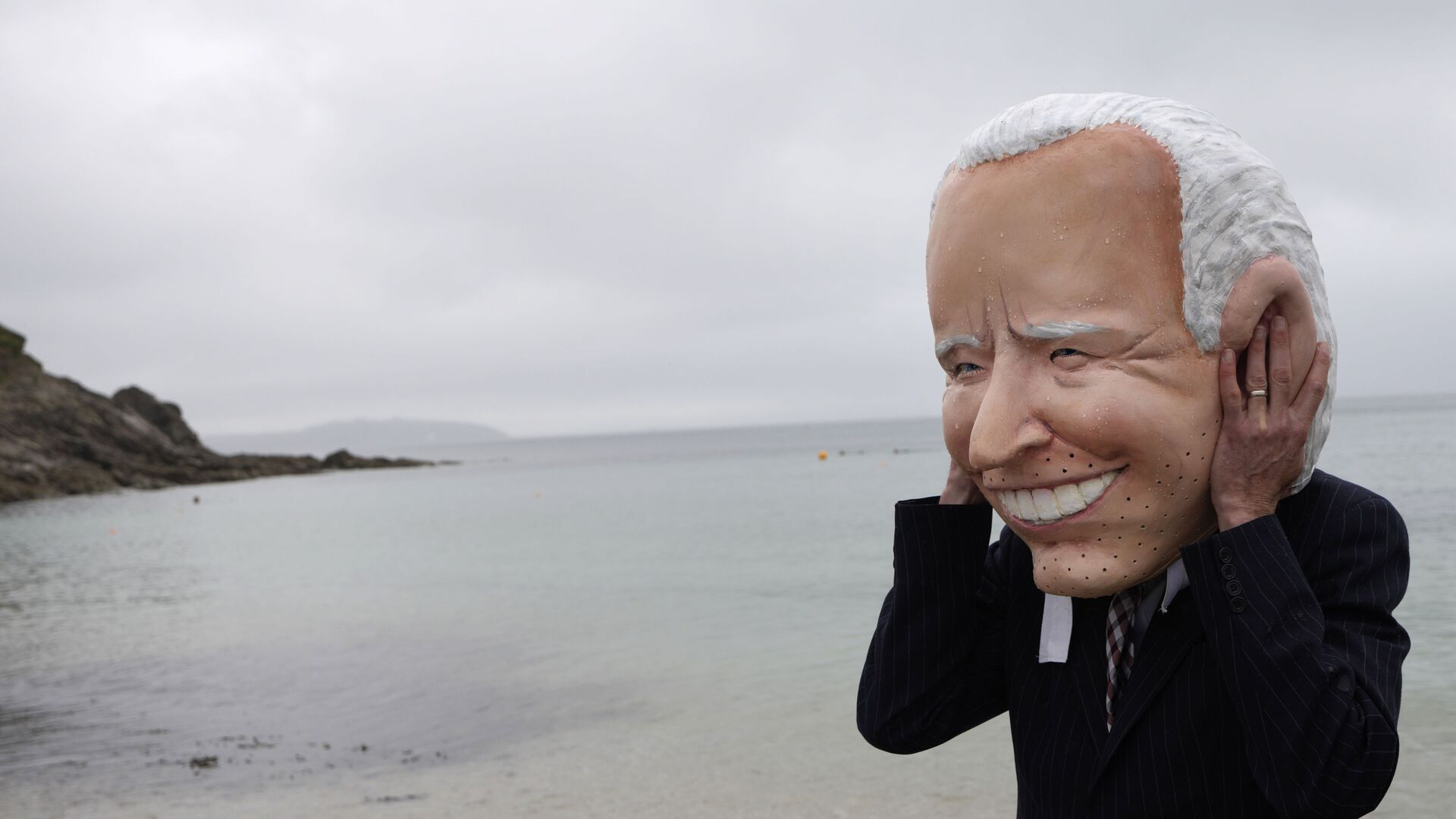 Активист с гигантской головой Президента США Джо Байдена готовится принять участие в акции НПО по вакцинам против COVID-19 на пляже Суонпул в Фалмуте, Корнуолл, Англия - Sputnik International, 1920, 12.09.2021