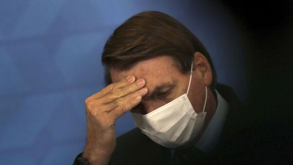 Brazil's President Jair Bolsonaro, wearing protective face mask, listens during a ceremony announcing economic measures to support philanthropic hospitals and help them treat COVID-19 patients, at the Planalto Presidential Palace, in Brasilia, Brazil, Thursday, March 25, 2021. - Sputnik International