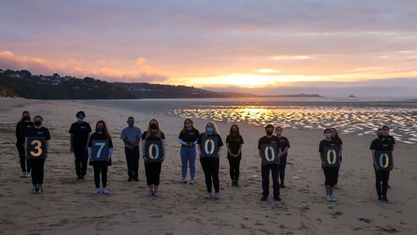 Activists from Crack the Crisis hold a vigil for the people around the world who have passed away due to the coronavirus disease (COVID-19) on the sidelines of G7 summit, at Porthkidney beach near Carbis Bay - Sputnik International