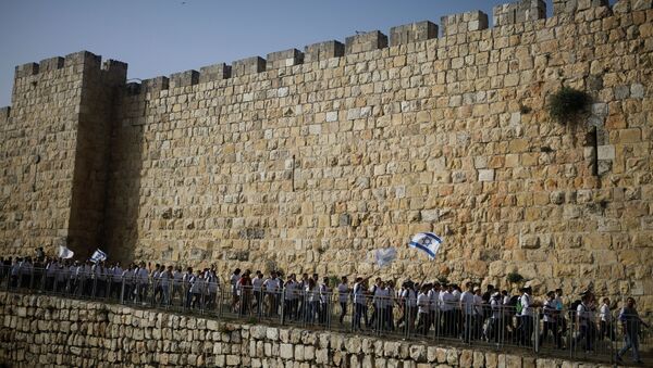 Youths wave Israeli flags during a parade marking Jerusalem Day amid Israeli-Palestinian tension as they march along the walls surrounding Jerusalem's Old City, May 10, 2021. REUTERS/Nir Elias/File Photo - Sputnik International