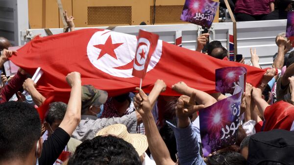 Demonstrators hold a Tunisian flag during a protest in Tunis, Saturday, June 5, 2021. Demonstrators will go to the streets of Tunis on Saturday to protest against the parliament and against the increase of the price in basic products announced this week by the government.  - Sputnik International