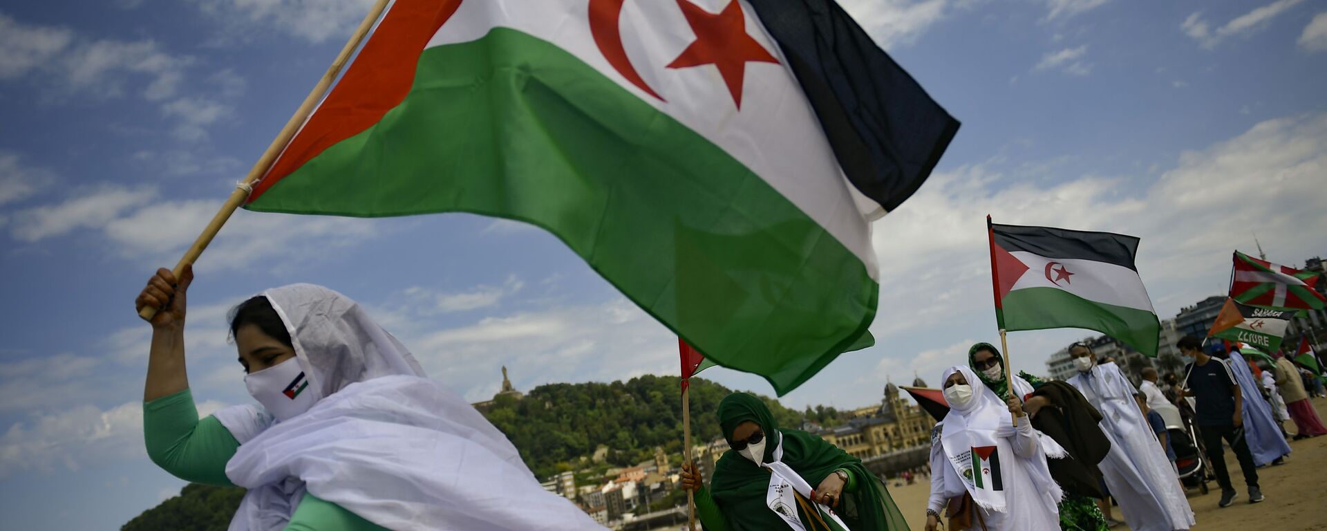 Saharan demonstrator wave their flags as they take part in a rally along the Concha beach support Brahim Gali, leader of the Polisario Front and a Sahara free, in San Sebastian, northern Spain, Sunday, May 30, 2021. Brahim Gali is recovering from COVID-19 in a Spanish hospital. The leader of the Western Sahara independence movement at the heart of a diplomatic spat between Spain and Morocco will appear before an investigating judge in Spain on June 1. - Sputnik International, 1920, 26.08.2022