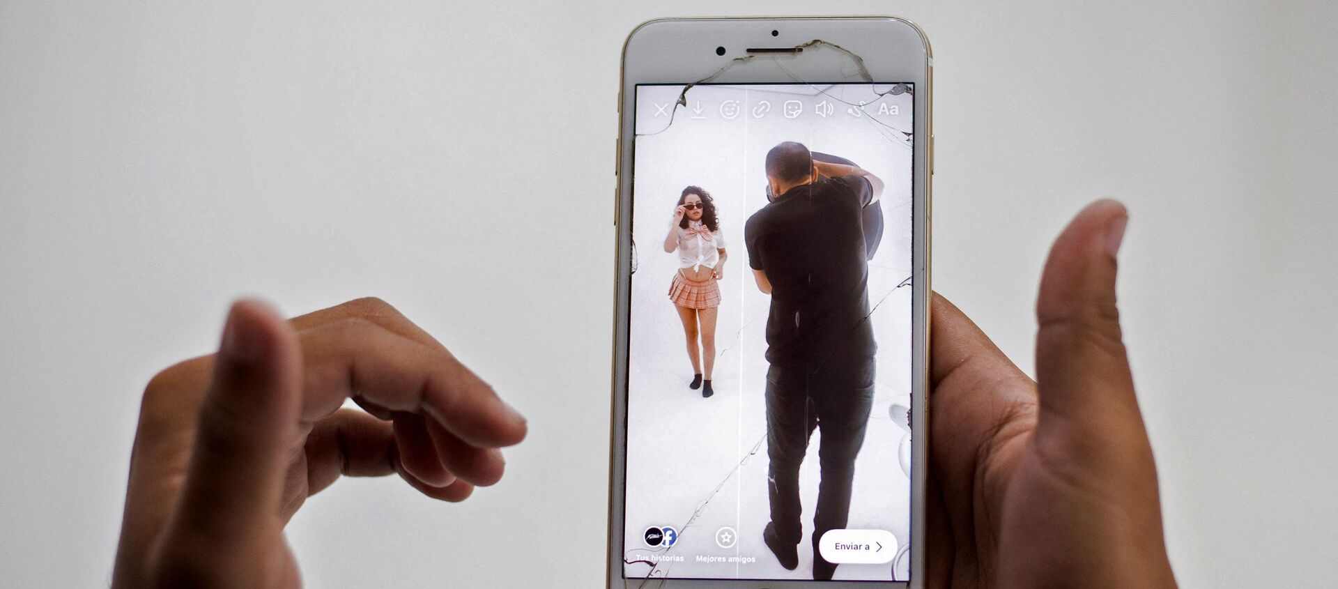 Valery Lopez is seen in a cellphone screen as she poses for pictures with photographer Michael Davis (R) during a photoshoot to make content for her OnlyFans profile, in Caracas, on December 1, 2020 - Sputnik International, 1920, 16.06.2021