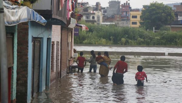 Nepalese people walk towards their flooded houses on the bank of the Bagmati river (File) - Sputnik International