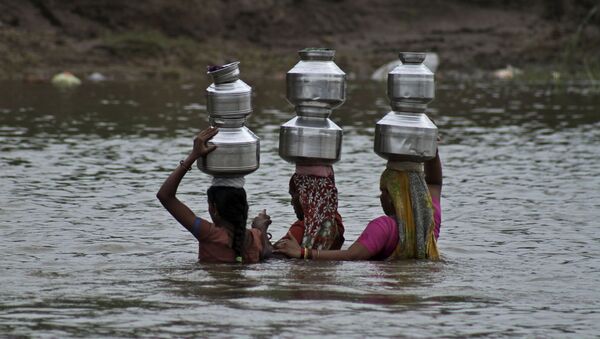 Indian women hold each other as they cross the River Heran after collecting drinking water near Sajanpura village in Chhota Udepur district of Gujarat state, India, Tuesday, Aug. 5, 2014 - Sputnik International