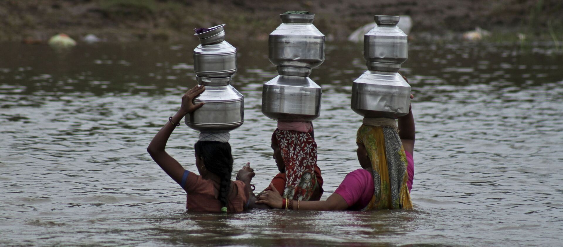 Indian women hold each other as they cross the River Heran after collecting drinking water near Sajanpura village in Chhota Udepur district of Gujarat state, India, Tuesday, Aug. 5, 2014 - Sputnik International, 1920