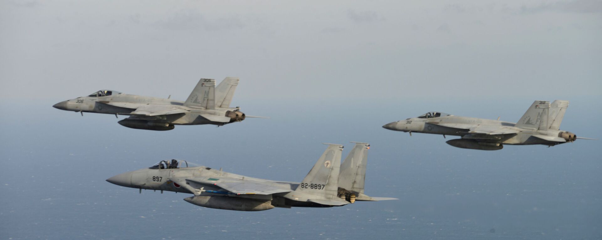 In this November 10, 2017, photo provided by the Japan Air Self-Defense Force, two US F/A-18, left, and right, and Japan Air Self-Defense Force's F-15 fly during a joint military exercise at an undisclosed location.  (Japan Air Self-Defense Force via AP) - Sputnik International, 1920, 19.01.2023