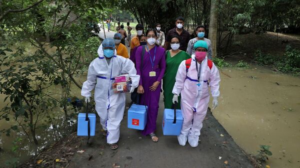 Healthcare workers carry COVISHIELD vaccine, a coronavirus disease (COVID-19) vaccine manufactured by Serum Institute of India, to inoculate villagers during a door-to-door vaccination and testing drive at Uttar Batora Island in Howrah district in West Bengal state, India, June 21, 2021 - Sputnik International