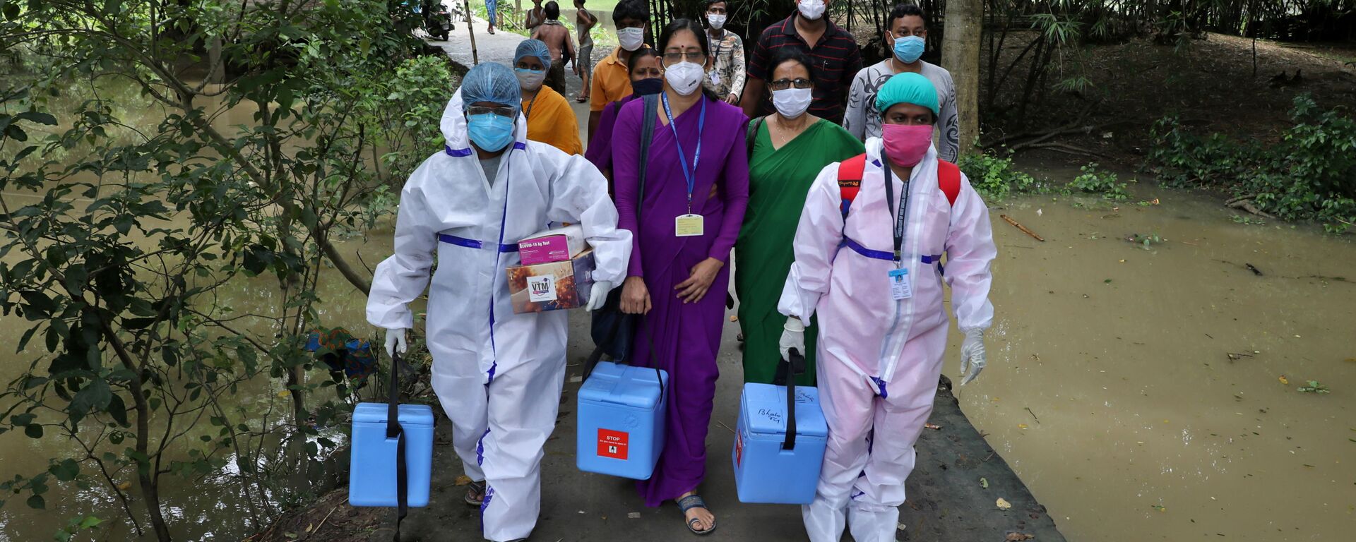 Healthcare workers carry the COVISHIELD vaccine, a coronavirus disease (COVID-19) vaccine manufactured by Serum Institute of India, to inoculate villagers during a door-to-door vaccination and testing drive at Uttar Batora Island in Howrah district in West Bengal state, India on 21 June 2021. - Sputnik International, 1920, 30.06.2021