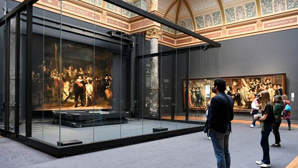 Poeple look at Rembrandt's famed Night Watch, which is back on display in what researchers say in its original size, with missing parts temporarily restored in an exhibition aided by artificial intelligence, at Rijksmuseum in Amsterdam, Netherlands June 23, 2021.  - Sputnik International
