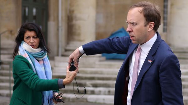 Britain's Health Secretary Hancock hands a microphone to his aide Coladangelo following a television interview outside BBC in London - Sputnik International