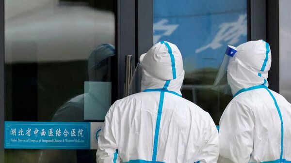 Staff members in protective suits stand at Hubei Provincial Hospital of Integrated Chinese and Western Medicine where members of the World Health Organization (WHO) team tasked with investigating the origins of the coronavirus disease (COVID-19) are visiting, in Wuhan, Hubei province, China January 29, 2021. - Sputnik International