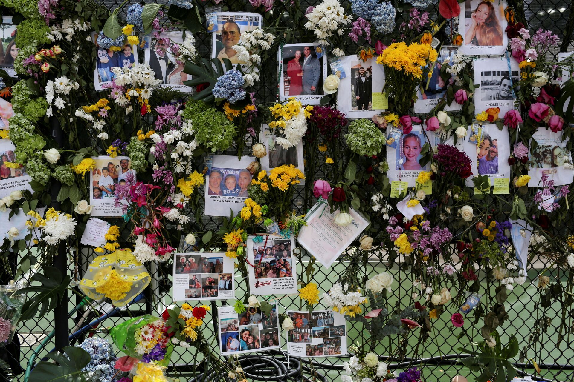 Photos and flowers hang in a fence at a memorial site created by neighbors in front of a partially collapsed residential building as the emergency crews continue search and rescue operations for survivors, in Surfside, near Miami Beach, Florida, U.S. June 29, 2021 - Sputnik International, 1920, 07.09.2021