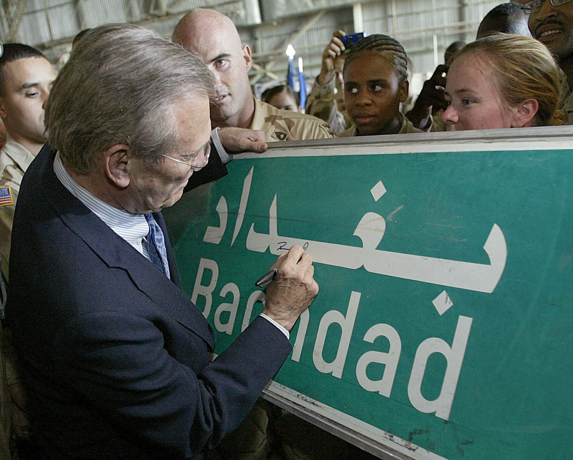U.S. Secretary of Defence Donald Rumsfeld (C) signs a Baghdad road sign at the request of a US soldier April 30, 2003 during his visit to US troops at Baghdad's international airport.  - Sputnik International, 1920, 07.09.2021