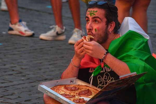 A fan of Italy eats pizza at the fan zone on Piazza del Popolo in Rome on 16 June 2021 while watching the UEFA EURO 2020 Group A football match on giant screens between Italy and Switzerland, played at the nearby Olympic Stadium. - Sputnik International