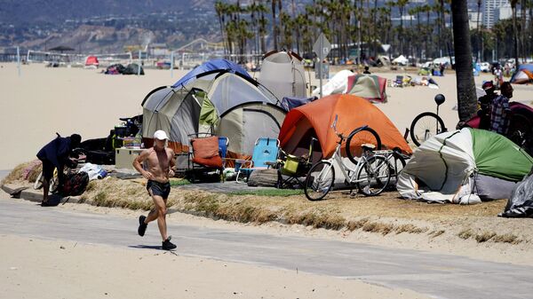 In this June 8, 2021, file photo, a jogger walks past a homeless encampment in the Venice Beach section of Los Angeles - Sputnik International