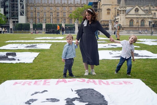 Moris and Assange's children stand in front of the posters, saying Free Assange. - Sputnik International