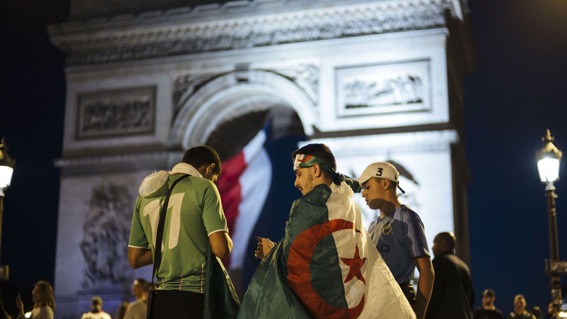Algerians fans check their phones as the Arc de Triomphe is seen in the background after the African Cup of Nations semifinal soccer match between Algeria and Nigeria in Paris, France, Sunday, July 14, 2019.  - Sputnik International, 1920, 02.10.2021