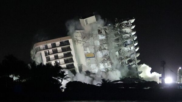 The remaining part of the partially collapsed 12-story Champlain Towers South condo building falls with a controlled demolition on July 4, 2021 in Surfside, Florida. The decision by officials to bring the rest of the building down was brought on by the approach of Tropical Storm Elsa and fears that the structure might come down in an uncontrolled fashion. Over one hundred people are missing as the search-and-rescue effort continues. - Sputnik International