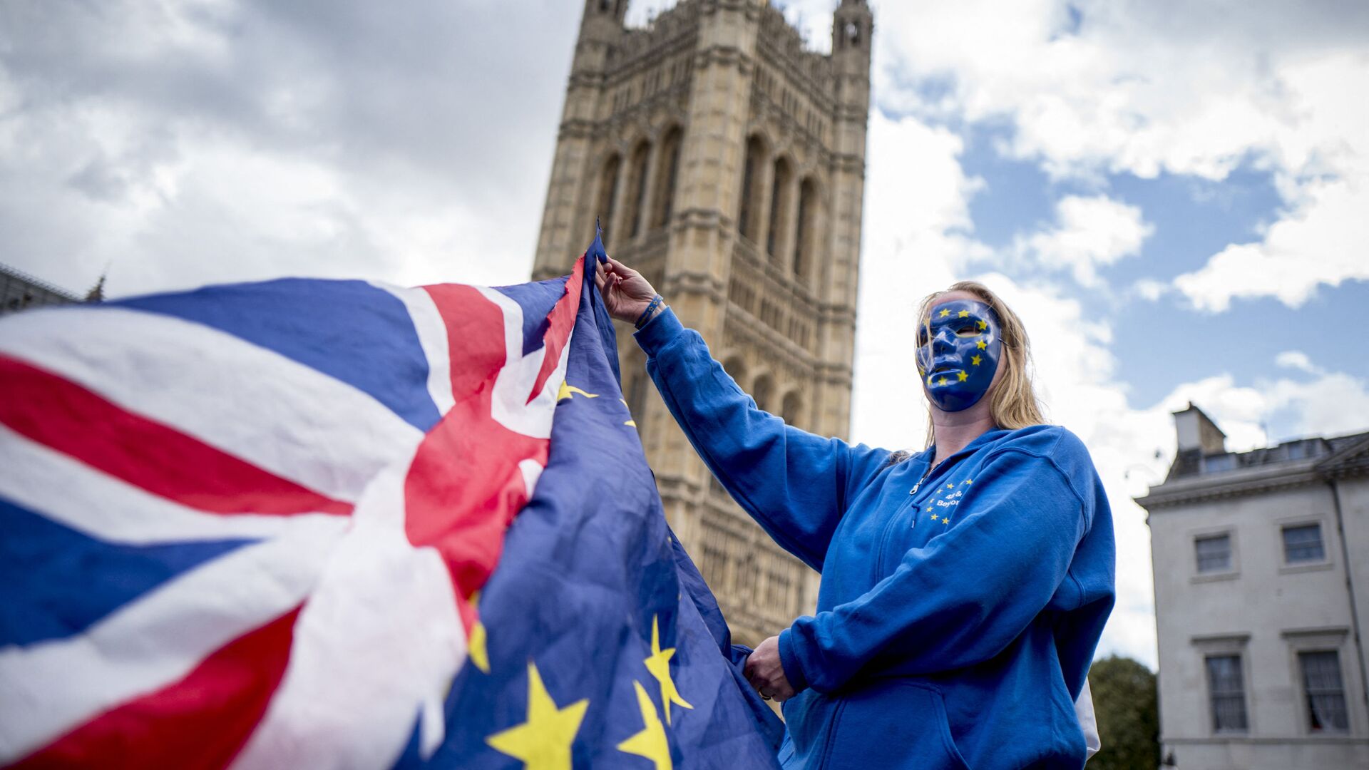 A Pro-European Union protester holds Union and European flags in front of the Victoria Tower at The Palace of Westminster in central London on September 13, 2017, ahead of a rally to warn about the terms of Brexit, by EU nationals in Britain and UK nationals in Europe - Sputnik International, 1920, 28.01.2022