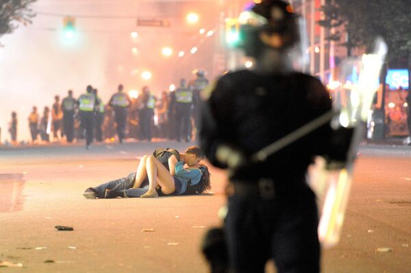 Riot police walk in the street as a couple kiss on 15 June 2011 in Vancouver, Canada.  - Sputnik International