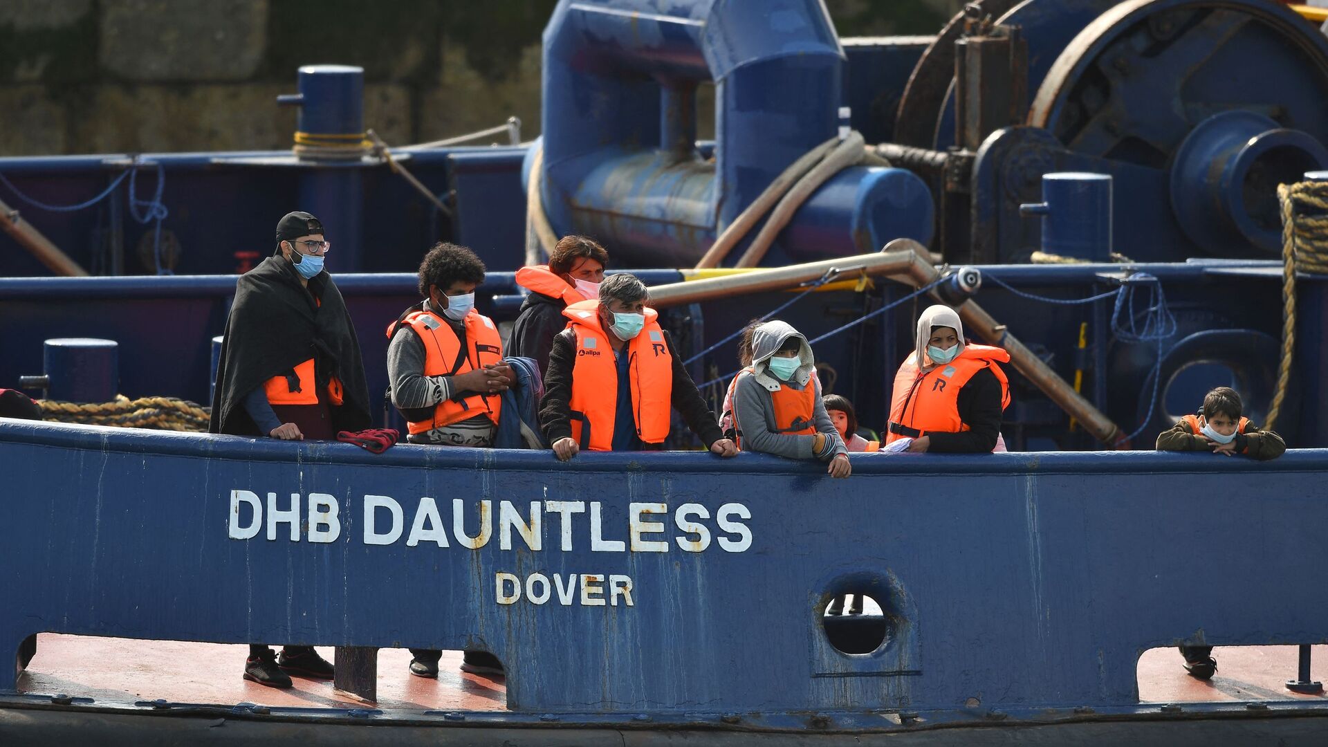 Waleed (3L), 29, a Kuwaiti migrant, stands with other migrants onboard the DHB Dauntless tug boat as they are brought to shore by the UK Border Force after illegally crossing the English Channel from France on a dinghy on September 11, 2020, in the marina at Dover, on the south coast of England - Sputnik International, 1920, 07.09.2021