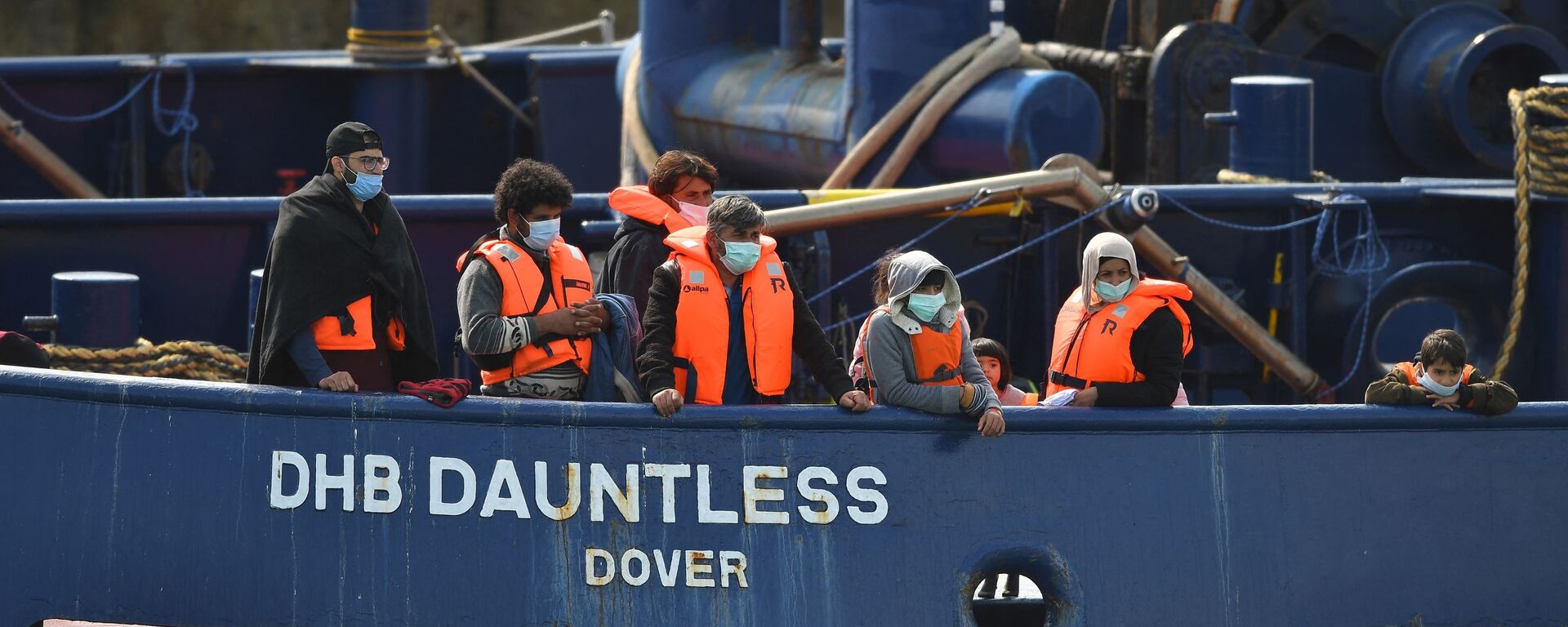 Waleed (3L), 29, a Kuwaiti migrant, stands with other migrants onboard the DHB Dauntless tug boat as they are brought to shore by the UK Border Force after illegally crossing the English Channel from France on a dinghy on September 11, 2020, in the marina at Dover, on the south coast of England - Sputnik International, 1920, 25.11.2021