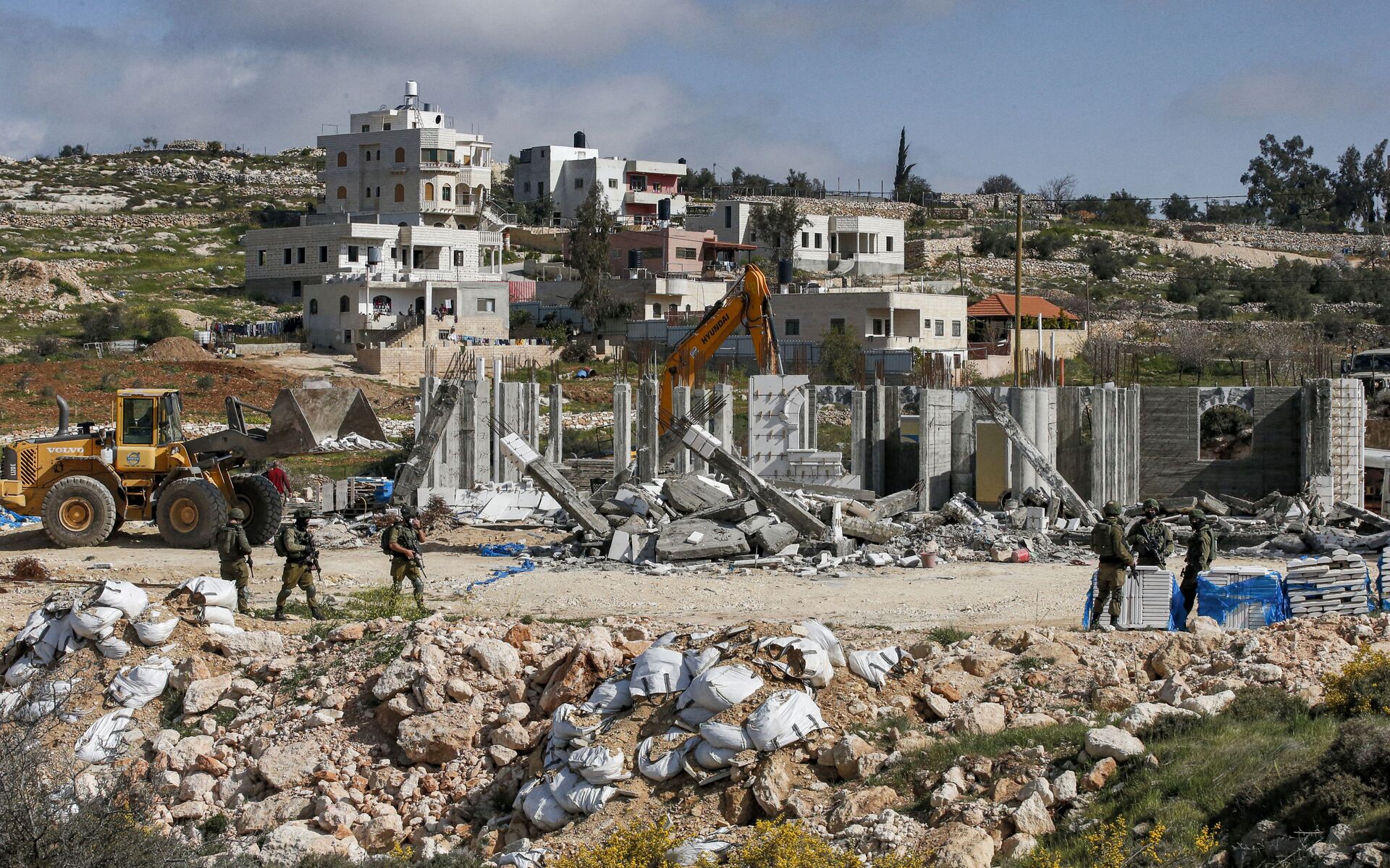 Israeli soldiers stand by as excavators demolish a Palestinian house (still under construction) located within the area C (where Israel retains full control over planning and construction) southeast of Hebron in the occupied West Bank on March 8, 2021. - Sputnik International, 1920, 07.09.2021