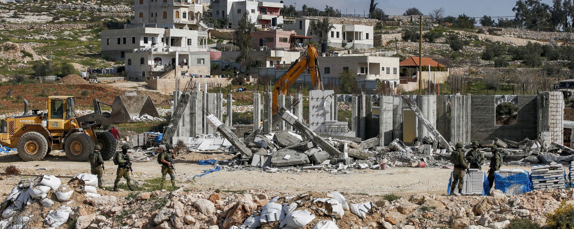 Israeli soldiers stand by as excavators demolish a Palestinian house (still under construction) located within the area C (where Israel retains full control over planning and construction) southeast of Hebron in the occupied West Bank on March 8, 2021. - Sputnik International, 1920, 08.07.2021