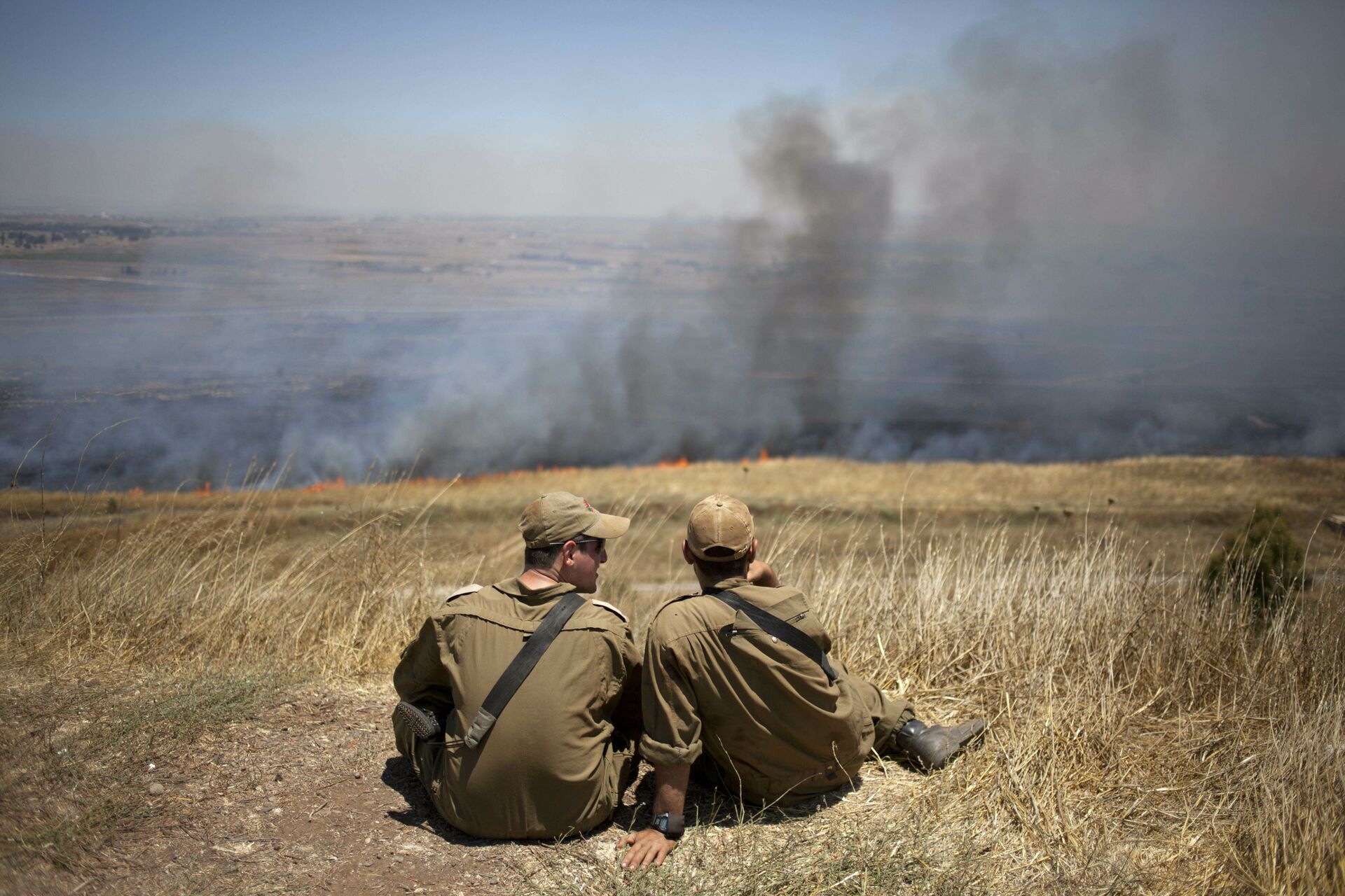 FILE - In this July 16, 2013, file photo, Israeli soldiers sit in a position on the border with Syria on the Israeli-controlled Golan Heights as smoke rises following explosions of mortar shells - Sputnik International, 1920, 07.09.2021