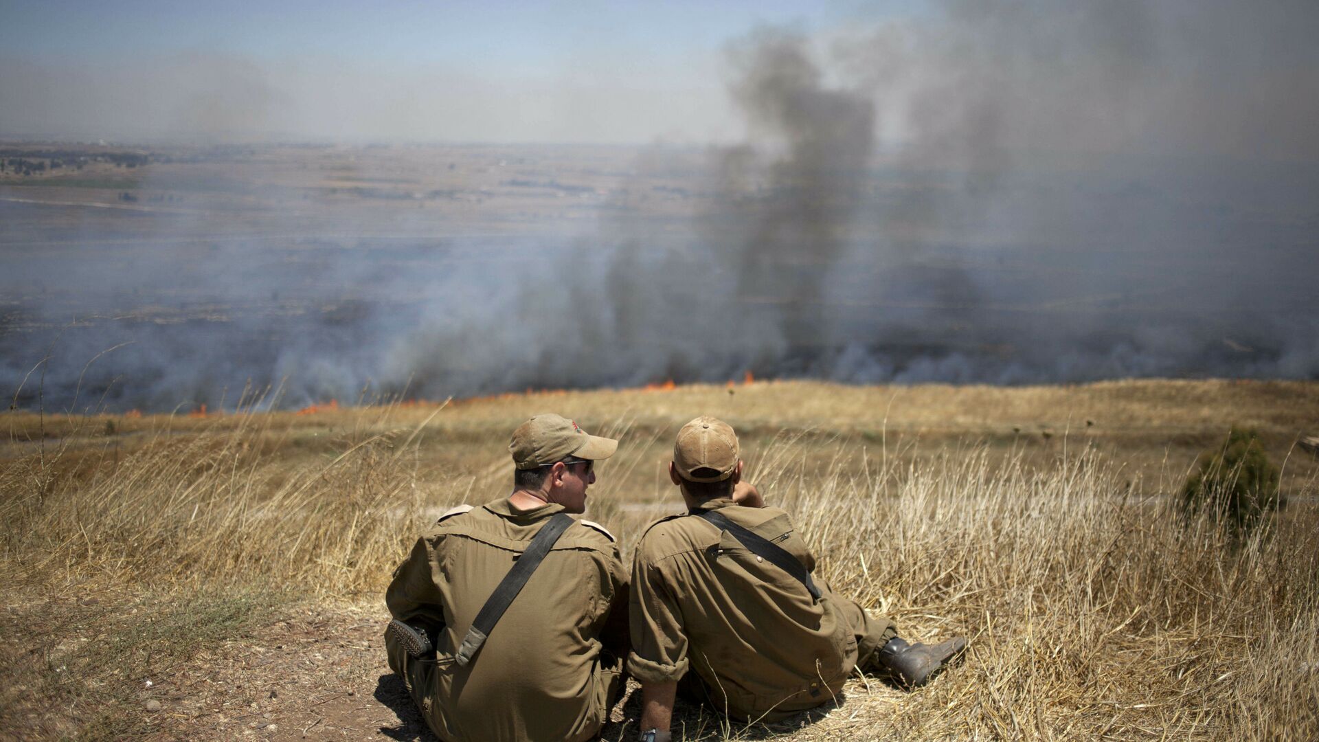 FILE - In this July 16, 2013, file photo, Israeli soldiers sit in a position on the border with Syria on the Israeli-controlled Golan Heights as smoke rises following explosions of mortar shells - Sputnik International, 1920, 16.10.2021